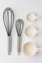 Two Whisks with Measuring Cups on White Background Top View Royalty Free Stock Photo