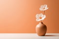 Two white anemone flowers in a peach fuzz color vase on minimal background