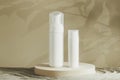 Two white blank plastic packaging cosmetic pump bottles for mousse foam cream and lotion stand on round podium, beach