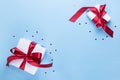 Two white boxes tied with a red satin ribbon bow on a blue background. Gifts for the holiday. Valentine`s day Royalty Free Stock Photo