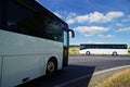 Two white buses passing through the intersection in a rural landscape