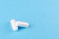 Two white capsules of nutritional supplement on blue background with copy space Royalty Free Stock Photo