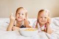 Two white Caucasian children girls eating corn puffs Royalty Free Stock Photo