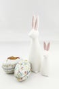 Two white ceramic easter rabbits and two coloured tin eggs