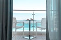 Two white chairs with a table on which stands a breakfast of coffee and croissants on the balcony with sea view.