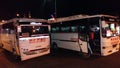 Two white city buses in the kemer at night