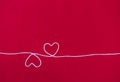 Two white cotton thread in heart shape on red fabric background Royalty Free Stock Photo