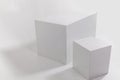 Two white cubes on white wall