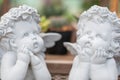 Two white cupid boys sculpture made of cement are in thinking action and looking to the sky Royalty Free Stock Photo