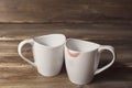 Two white cups, one of them is wearing lipstick, the relationship of men and women, on the background of old wooden