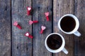 Two white cups with tea or coffee on a wooden background. Little red clothespins hearts Royalty Free Stock Photo