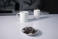 Two white cups of tea next to used tea bags on white table in gray kitchen