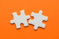 Two white details of puzzle on orange background Royalty Free Stock Photo