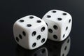 Two white dices falling on table on black background