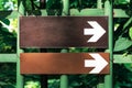 Two white directional arrow road sign point to the right in the park against the background of green trees Royalty Free Stock Photo