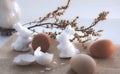 Two white Easter bunnies next to brown eggs on a beige tablecloth stand on the window . Decoration for the celebration of Easter Royalty Free Stock Photo