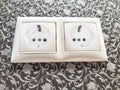 Two white European power outlets mounted on ornate wall. European Dual Socket on a Patterned Wall