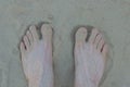 Two white feet on the legs of a man in gray sand Royalty Free Stock Photo