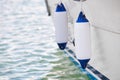 Two white fenders suspended between a boat and dockside for protection. Maritime fenders Royalty Free Stock Photo