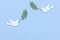 Two white figurines of a doves of peace with olive tree branch in their beaks on the light blue background. Peace Concept Royalty Free Stock Photo