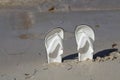 Two white flipflops sticking out of the sand Royalty Free Stock Photo