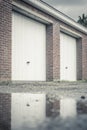 Two white garage doors with vertical lines, set into a red brick wall Royalty Free Stock Photo