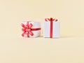 Two white gift boxes red ribbon bow on cream beige background. Royalty Free Stock Photo