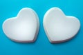 Two white glossy porcelain hearts on a light blue background; Wedding card; A love note.