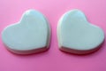 Two white glossy porcelain hearts on a pink background; Wedding card; Copy space