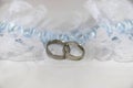 Two white gold wedding rings on white lace pad and blue garter Royalty Free Stock Photo