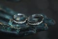 Two wedding rings on metal Buddha hand dark background. Spiritual love concept. Royalty Free Stock Photo