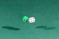 Two white and green dices falling on a green table Royalty Free Stock Photo