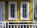 Two white house windows with glass, green curtain decoration on the yellow wooden resident. Royalty Free Stock Photo