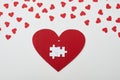 Two white interlocked puzzle pieces over red heart