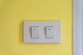 Two white lighting switchs on yellow concrete wall Royalty Free Stock Photo