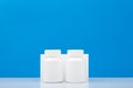 Two white medication bottles against blue background with copy space. Royalty Free Stock Photo