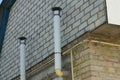 Two White Metal Chimney Pipes On A Brick Wall