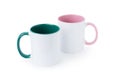Two white mugs, with a green and pink handle on a gray background.