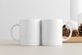 Two white mugs mockup with candles on a table. Christmas decoration