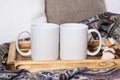 Two white mugs, pair of cups on a wooden tray, the Mockup. Cozy home, wooden background, cotton and wool decorations, winter gifts