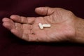 Two white pills in old men`s hands . Painful old age. Royalty Free Stock Photo