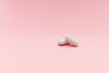 Two white pills on pink background with red heart shape, femine cure Royalty Free Stock Photo