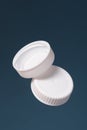 Two white plastic bottle caps on a blue background. Front and back of the cap. Royalty Free Stock Photo