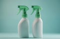 Two white plastic spray bottles with green trigger tops stand on light blue studio background. Identical dispenser containers Royalty Free Stock Photo