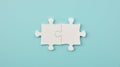 two white puzzle pieces matching together againt light blue background Royalty Free Stock Photo