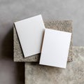 Two white rectangular papers placed on top of a textured stone block against a gray background Royalty Free Stock Photo