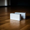 Two white rectangular yoga blocks rest on a polished wooden floor, casting soft Royalty Free Stock Photo