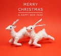 Two white reindeer decoration at red background with copy space for your own text