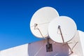 Two white satellite dishes on house wall