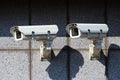 Two white security cameras on the concrete wall